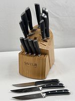 Full view of Saveur Selects knife set with bamboo holder and additional knives laid in front.