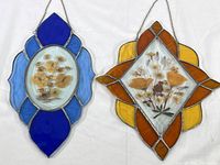 Both stained glass window hangers side by side showing overall shape, colors, and pressed flower details.