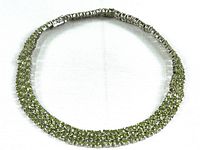 Full view of the sterling silver bracelet with two rows of green crystals arranged in prong settings against a white background.