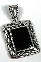Front view of sterling silver rectangular pendant with patterned border and black inlay.