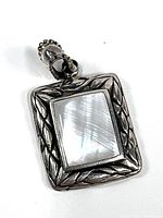 Front view of silver pendant showing iridescent mother of pearl central inlay and detailed silver rope design border.