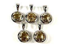 Top-down photo showing all five round yellow crystal pendants in sterling silver bezels arranged in two rows.