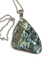 Close-up of triangular abalone shell pendant with sterling silver setting and chain.