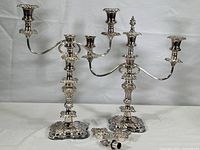 Two fully assembled silver tone two-arm candelabras shown side by side on white background.