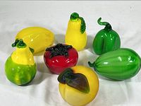 Seven vintage glass fruit figurines in yellow, green, red colors on white background