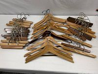 Overview of all wood hangers laid out on a table, showing different styles including curved shoulder hangers and clamp hangers for slacks or skirts.