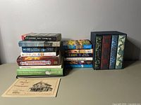 Photo showing stacks of various adult books including fiction, history, and boxed sets.