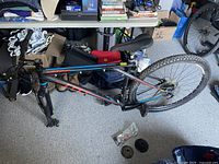 Overall view of bike frame assembly with seat, handlebars, rear wheel and spare parts bag