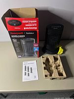 Photo showing Honeywell heater next to its original box, instruction manual, and packaging insert on a table.