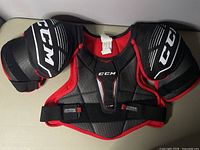 Full view of black and red CCM Jetspeed hockey shoulder pads, new condition.