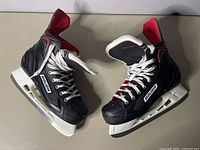 Pair of Bauer X250 Vapor black and red hockey skates viewed from the outside side angles showing the overall condition and markings.