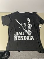 Front view of black men's T-shirt with white Jimi Hendrix graphic and name text.
