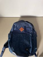 Front view of the blue Ripzone backpack showing main compartment and front zippered pocket with leaf pattern.