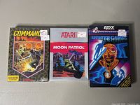 Front view of three sealed Atari 2600 game boxes: Commando, Moon Patrol, Winter Games with price tags