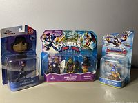Photo showing three Toys to Life figures/packages side-by-side: Disney Infinity Hiro figure, Skylanders Trap Team Mirror of Mystery Adventure pack, and another Skylanders packaged figure.