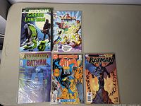 Four comic books laid flat, featuring Green Lantern, Voltron, and Batman comics including Anniversary Issue #400 and Detective Comics.