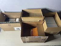 Photo of several empty cardboard boxes and a roll of thermal paper inside one box.