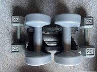 Top view showing two 25 lb cast iron hex dumbbells and two smaller light gray plastic dumbbells with smooth finish