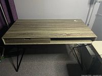 Top view of the wooden desk showing wood grain surface, single drawer, and cable hole