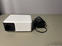 Side angle showing the Yoton mini projector and the black power cord beside it.