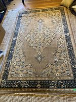 Full view of rectangular traditional patterned area rug placed on floor, showing general design, colors, and border.