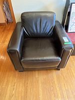 Front view of brown leather-like armchair, showing seat, back, armrests, and condition.