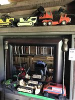 Six metal Tonka toy vehicles arranged on a wooden shelf showing various construction vehicle types and paint wear
