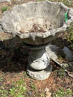 Concrete bird bath with large shallow basin and detailed edges from a front angle
