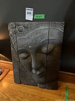 Full front view of the concrete Buddha wall plaque showing the face and crack