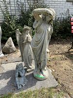 Group shot of three outdoor concrete statues on a concrete slab: tall woman figure, praying angel, and seated cherub angel. Tallest is 33 inches.