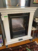 White electric fireplace with black insert and molded trim on caster wheels