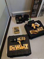 Two yellow and black DeWalt cordless drills and cases, battery charger and battery pack, 21 piece cobalt drill bit set.