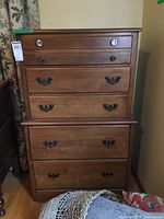 Front view of a 5-drawer wooden dresser with mixed drawer pulls and a brown finish.