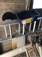 Photo showing the aluminum extension ladder horizontally positioned with the black plastic ladder saddle mounted on it; close-up of ladder rungs and saddle.