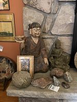 Lot overview including wooden figurine, green statue, framed print, and assorted rocks.