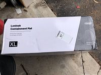 Top view of boxed Loninak containment mat with XL size label, showing dimensions 8'6" x 22' and all-season all-weather usage.