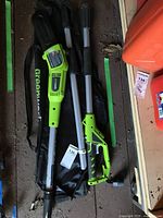 Full view of the assembled tree trimmer parts laid out including main unit, detachable poles, handle, protective chain guard, and carrying bag.