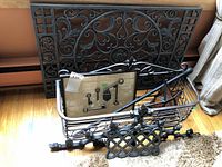 Large wrought iron decorative pieces stacked against wall including decorative panel, planter and trivet items.