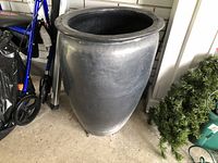 Full view of large black/dark gray clay planter with rounded shape and wide rim.