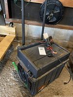 Photo showing full view of the MotoMaster Eliminator unit positioned on floor, revealing black plastic housing and attached wires.