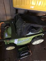 Photo of the green Neuton electric lawnmower with attached black grass collection bag, showing overall condition and branding.