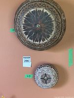 Two painted gourds displayed on a wall, showing overall designs and size comparison