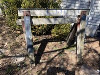 Front view of one wooden saw horse, showing metal brackets and weathered wood