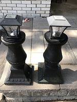 Pair of black outdoor solar lights on decorative hollow posts with square lantern tops