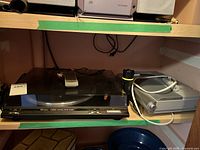 Technics SL-BD20 turntable and Sony AM/FM CD player on a shelf with cables and remote on top