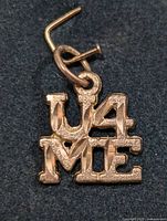 Front view of the pendant showing 'U4ME' lettering and the bail.