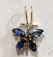 Close-up photo of 10KT gold pendant with four marquise-cut blue sapphire stones arranged in a symmetrical design.