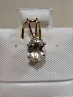 Front view of the oval aquamarine gemstone set in 14KT gold fill pendant on white display stand.