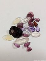 Photo showing a collection of assorted genuine loose gemstones of various shapes and colors, totaling around 10 carats.