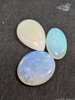 Photo of three Australian opal cabochons on black background showing colors and shapes